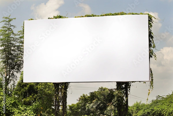 Fototapeta Billboard on rural area of India, outdoor advertising, mockup billing board in front of green tree and Blank white background for branding design large hoarding. Outdoor advertising construction.