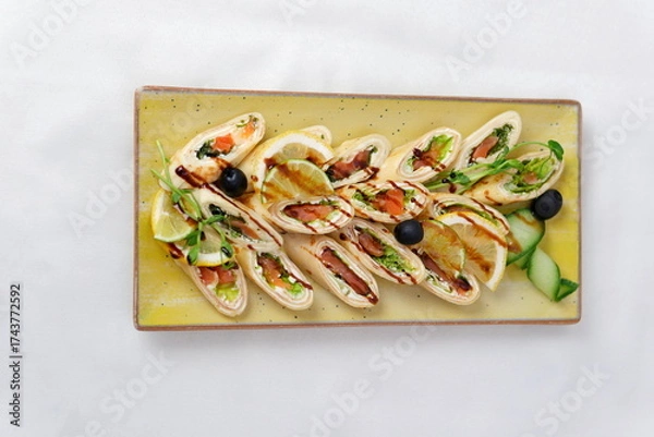 Fototapeta Rolls vegetables olives Delicious rolls of fried zucchini slices and feta cheese with rucola, served with olive oil and pieces of bell peppers