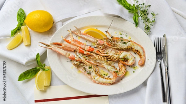 Fototapeta three halved scampi in a plate with lemon and lime on the table