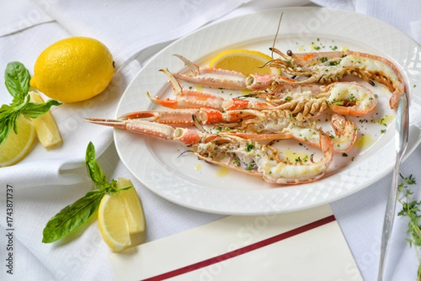 Fototapeta three halved scampi in a plate with lemon on the table