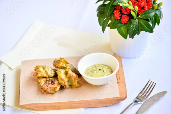 Fototapeta baked zucchini flowers in a white plate on a cutting board with sauce on a white background with a flower