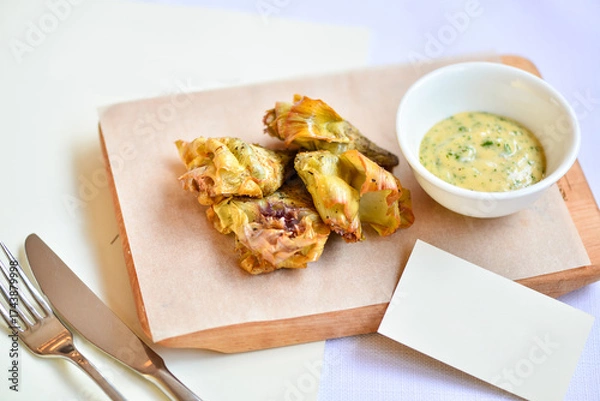 Fototapeta baked zucchini flowers in a white plate on a cutting board with sauce on a white background