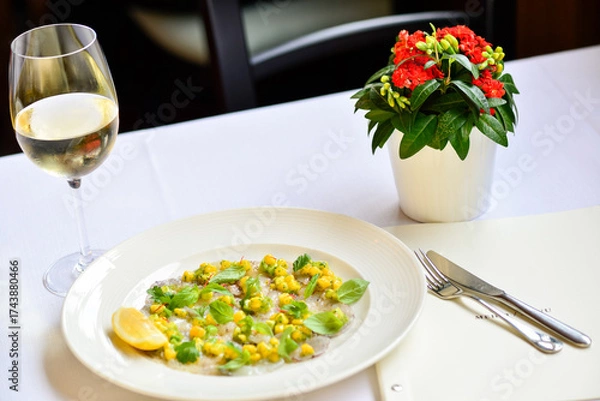 Fototapeta Fish carpaccio decorated with corn and basil on a plate with wine