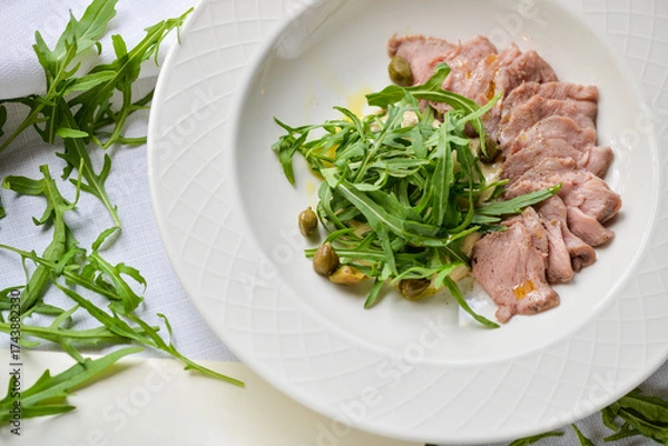 Fototapeta sliced ​​meat on a plate with arugula