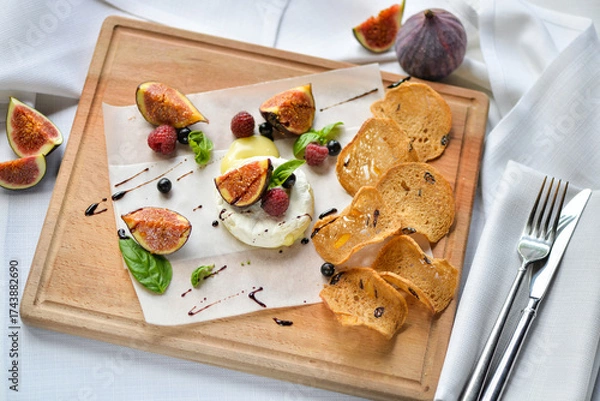 Fototapeta figs drizzled with balsamic sauce on a wooden board with camembert cheese and bruschetta