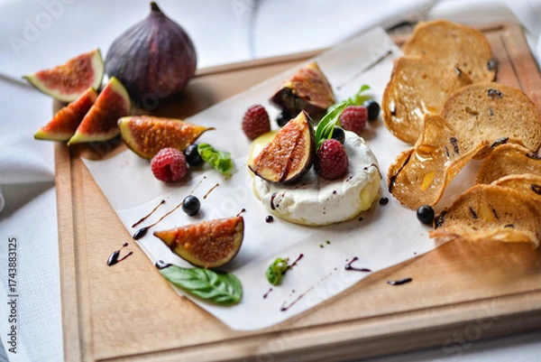 Fototapeta figs drizzled with balsamic sauce on a wooden board with camembert cheese and bruschetta macro photo