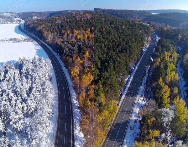 Fototapeta Autumn road through snowy forest