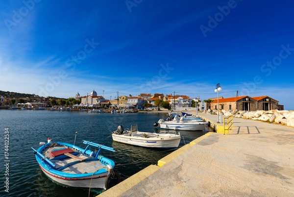 Fototapeta Krajobraz z niebieskim niebem i łodziami rybackimi w porcie na greckiej wyspie Lesbos położonej nad Morzem Egejskim,
