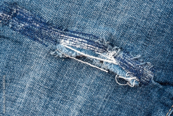 Fototapeta Hole in jeans close-up. Texture of faded denim