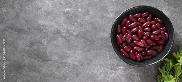 Fototapeta A bowl of red kidney beans placed on a textured grey stone background- showcasing natural color and simplicity.