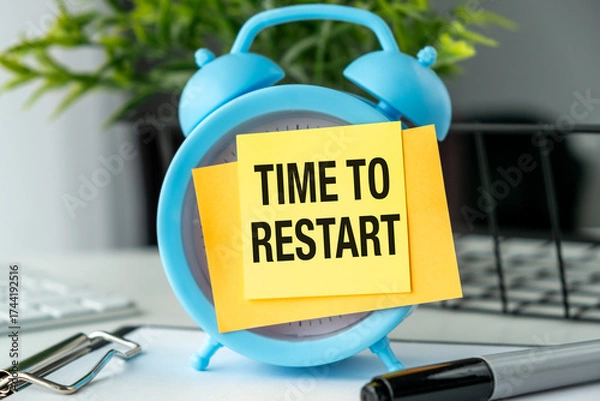 Fototapeta A blue alarm clock with a yellow note that says Time to Restart on it