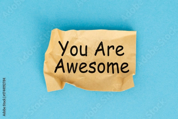 Fototapeta A torn piece of paper with the word You Are Awesome written on it. The paper is crumpled and has a sense of urgency