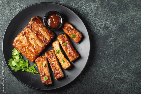 Fototapeta Hot grilled spare ribs from a summer BBQ served on a plate with sauce. Top view. Copy space