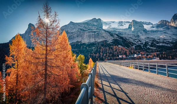 Fototapeta Huge mountain range on background on walkway on dam on Fedaia lake. Incredible autumn view of Dolomite Alps. Gorgeous morning scene of Italy, Europe. Traveling concept background.