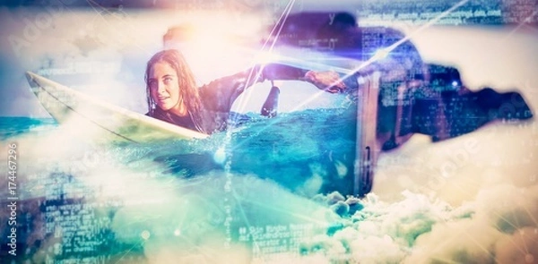 Fototapeta Composite image of woman in wetsuit with a surfboard on a sunny