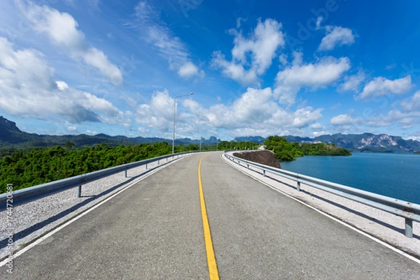 Fototapeta Asphalt road on the dam with blue sky and cloud background.