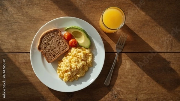 Fototapeta healthy breakfast of toast with avocado, scrambled eggs and a glass of orange juice