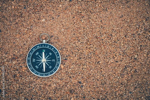 Obraz Navigation compass resting on beach sand.