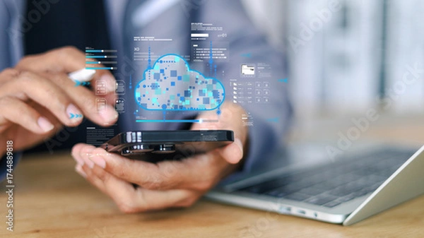 Fototapeta Businessman using smartphone and laptop with cloud computing technology for online data management, secure file transfer, and digital business connection in modern workplace.