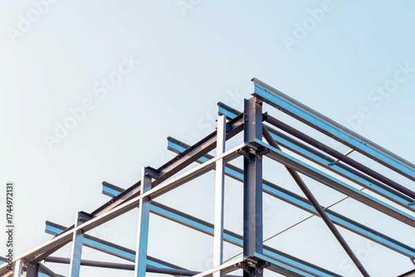 Fototapeta Framework of  modern steel frame building erected against a clear sky during the day showcasing steel construction and architectural design