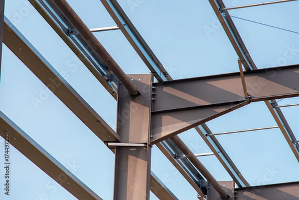 Fototapeta Close-up of steel frame structure elements and connection points against blue sky
