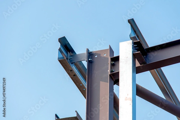 Fototapeta Close-up of steel frame structure elements and connection points against blue sky
