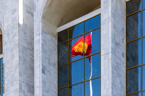 Fototapeta National Flag of Kyrgyzstan reflecting on modern building windows in urban setting