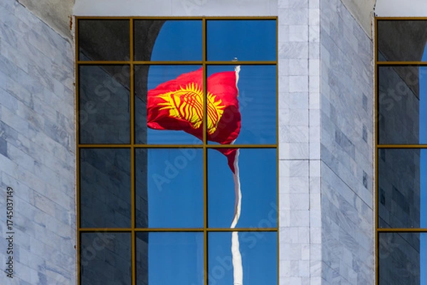 Fototapeta Waving National Flag of Kyrgyzstan reflected in building window under blue sky