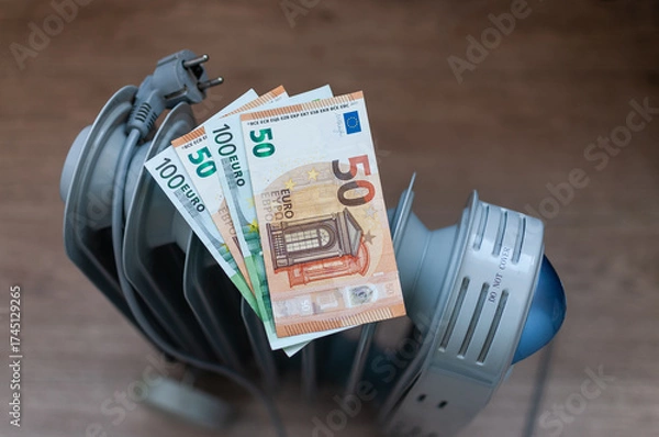 Obraz Euro banknotes lie on an electric radiator, symbolizing the high cost of electricity and heating. Rising energy prices. Concept of an energy crisis. Social problems. 