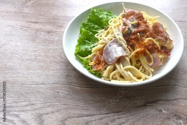 Obraz fried spaghetti white cabonara cream sauce topping slice crispy pork bacon and lettuce on plate 