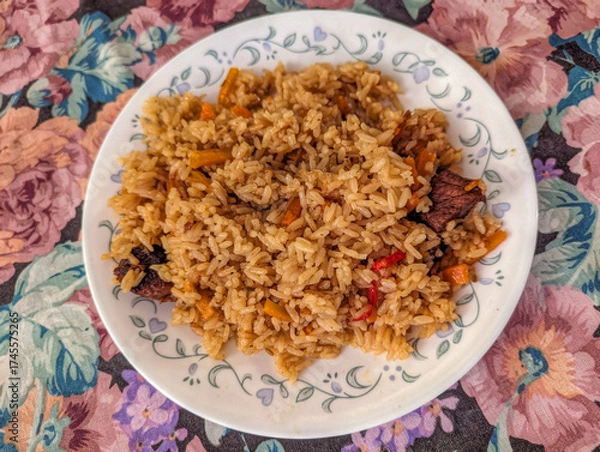 Obraz Uzbek Plov Rice Dish with Beef and Vegetables Served on a Floral Tablecloth