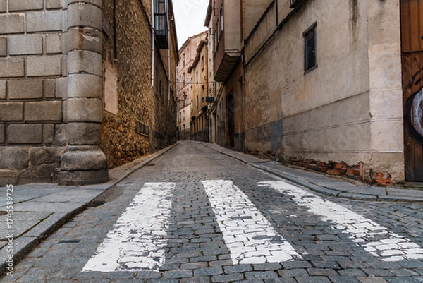 Fototapeta Cobblestone street in Segovia, Spain, with a pedestrian crossing.