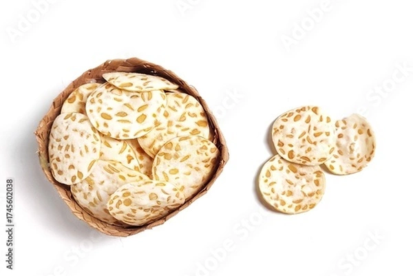 Fototapeta Top view of Keripik Tempe or Tempeh Chips in bamboo basket. Isolated on white background with copy space. Traditional Indonesian food are made from soybeans mixed with rice flour then sliced ​​thinly.