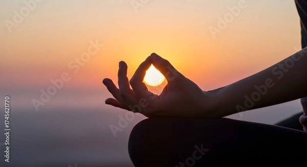 Fototapeta A person meditating with hand gesture against the setting sun in a peaceful outdoor setting