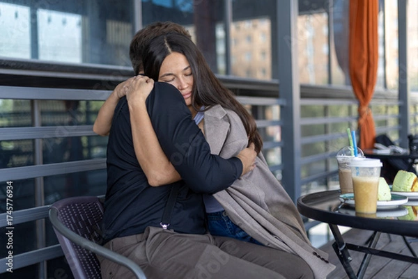 Fototapeta a young couple sitting in a coffee shop, hugging each other.