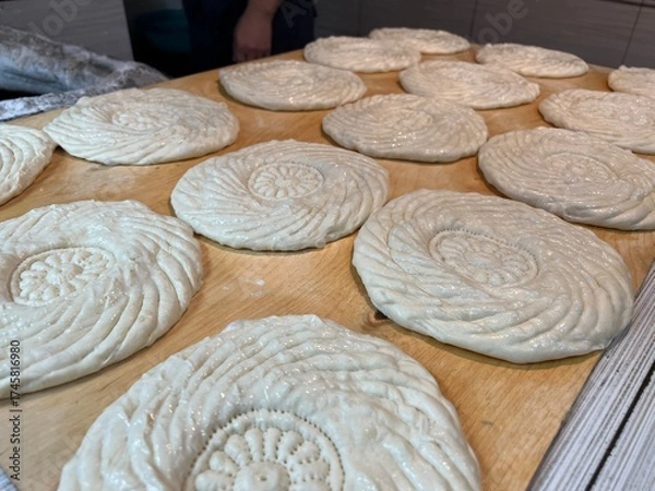 Fototapeta Traditional Uzbek round flatbreads are prepared for baking in a tandoor