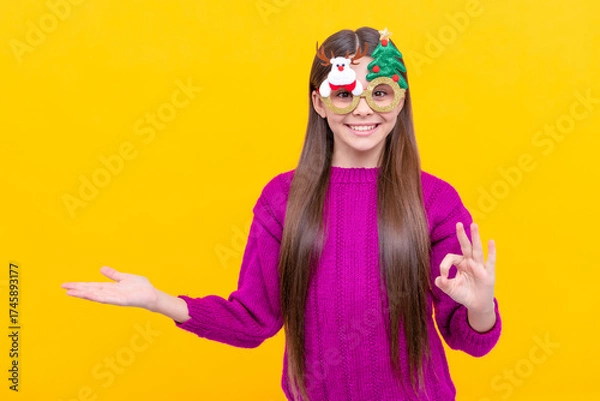 Fototapeta happy kid in party glasses presenting product on yellow background, new year