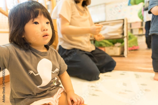Obraz 保育園で先生の話を聞く女の子の幼児