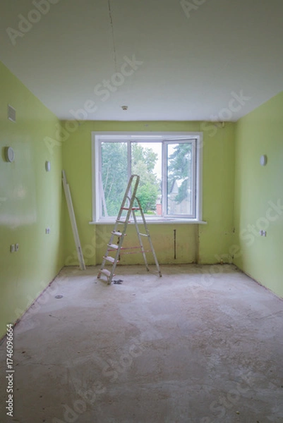 Fototapeta room is being renovated, featuring bright green walls and window that lets in natural light. ladder stands in center, awaiting further work on unfinished floor. close up.