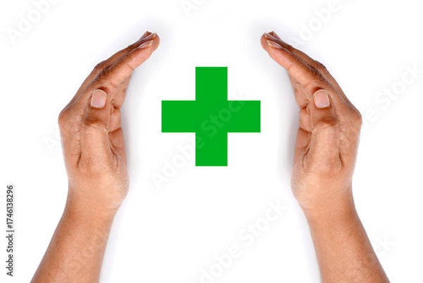 Obraz Green medical cross covered by hands on white background.