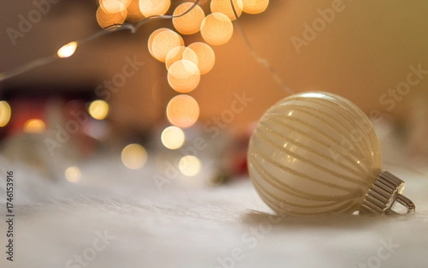 Fototapeta Clean christmas bauble on white wool with bokeh lights background.
