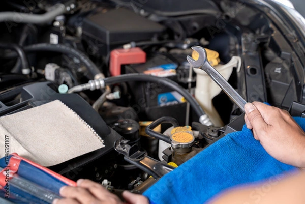 Fototapeta A young man works on fixing an engine by himself at home, showing DIY maintenance and mechanical skills.