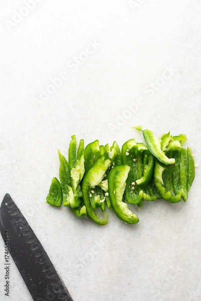 Fototapeta Overhead view of green bell peppers being sliced on a marble countertop, top view of green bell peppers