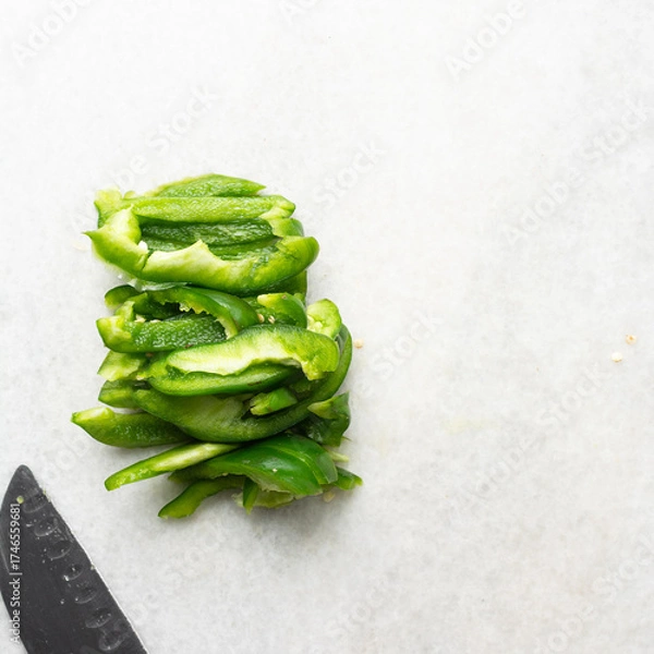 Fototapeta Overhead view of green bell peppers being sliced on a marble countertop, top view of green bell peppers