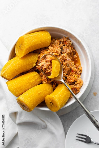 Fototapeta overhead view of Boiled ripe plantain with tomato scrambled eggs in a white bowl, top view of nigerian egg and plantain
