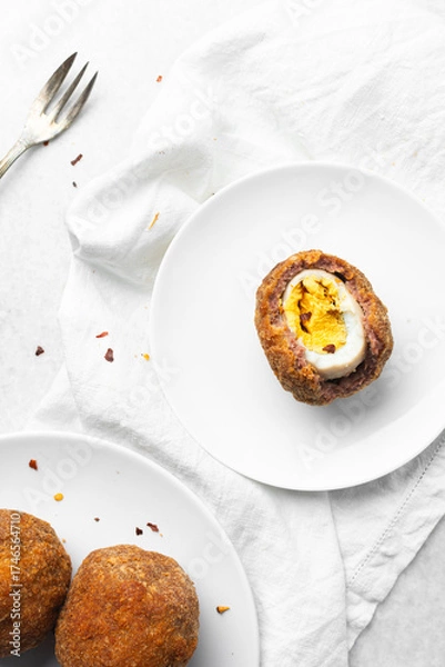 Fototapeta Overhead view of fried scotch eggs on white plate, top view of cross-section of scotch eggs on white dish