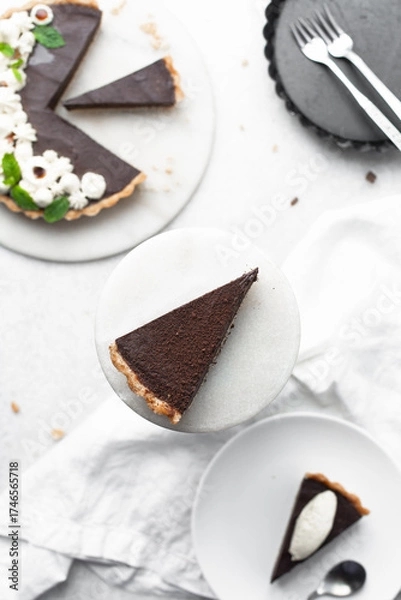 Fototapeta Overhead view of a slice of chocolate tart on a white plate, top view of no bake chocolate tart on a white background