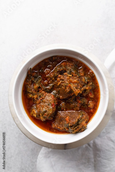 Fototapeta Overhead view of miyan taushe in a white bowl, top view of northern nigerian miyan taushe soup on a white countertop	