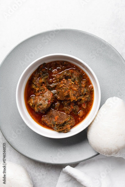 Fototapeta Overhead view of miyan taushe and tuwon on a white plate, top view of northern nigerian miyan taushe soup and rice swallow or tuwon shinkafa