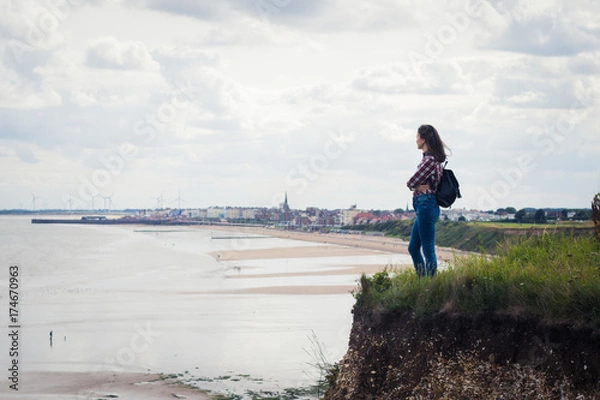 Fototapeta Young girl stands on the cliff near the sea